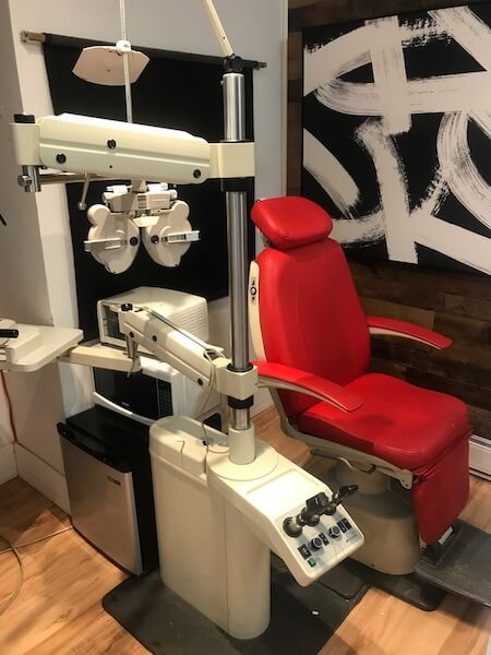 Sur cet image vous y voyez l'intérieur de la salle destinée au examen de la vue à La Boîte à Lunettes sur St-Denis à Montréal alors qu'une chaise en cuir rouge est là à côté de l'outil par excellence de l'Optométriste membre du Team.